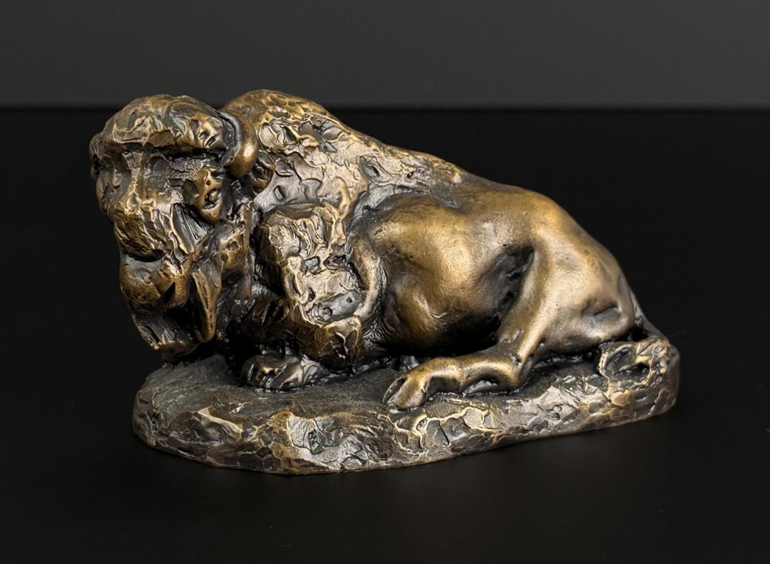 Daro Flood Reclining Buffalo Bronze: Title is Reclining Buffalo. 4 1/2" by 2 1/2" by 2 1/2". 9/30 Daro Flood (1954 - 2017) was active/lived in Arizona. Daro Flood is known for Portrait bust Indian and cowboy sculpture. Daro Flood was a j