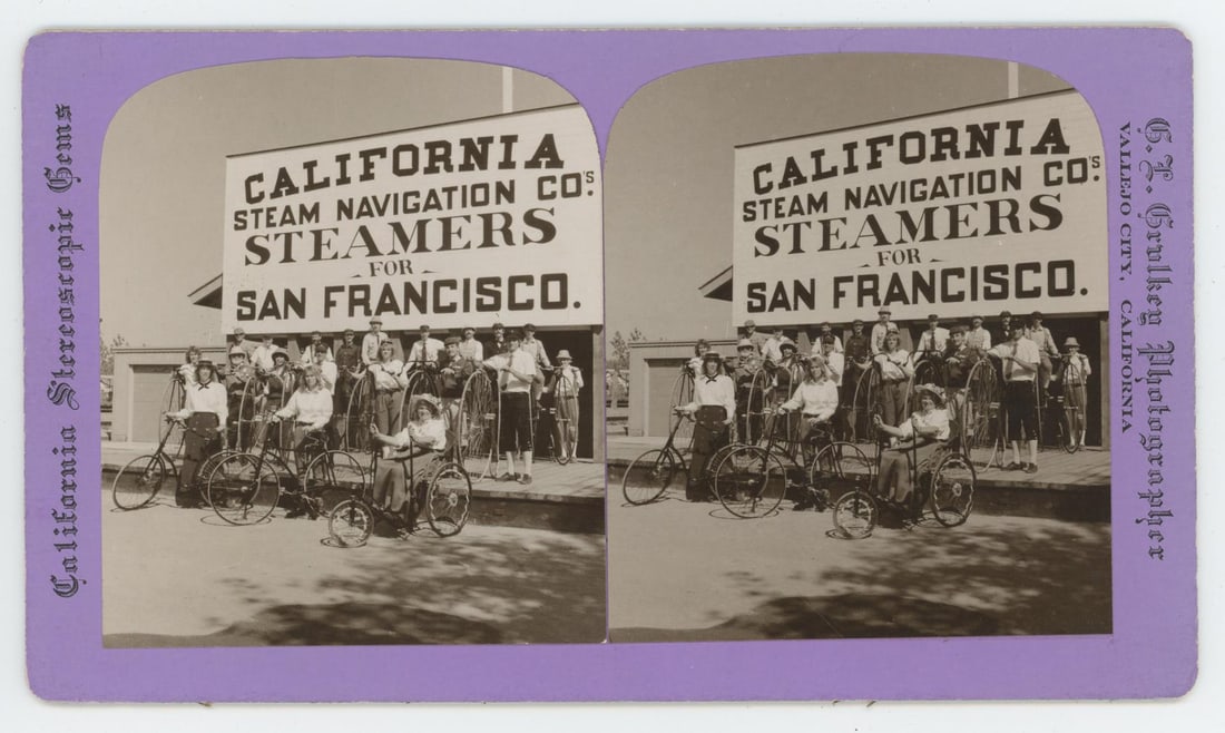 Grulkey California Wheelman Tour Stereoview: Farthing high wheel bicycles, safety bicycles and tricycles in front of the California Steam Navigation company sign. Card by G.L. Grulkey Photo.