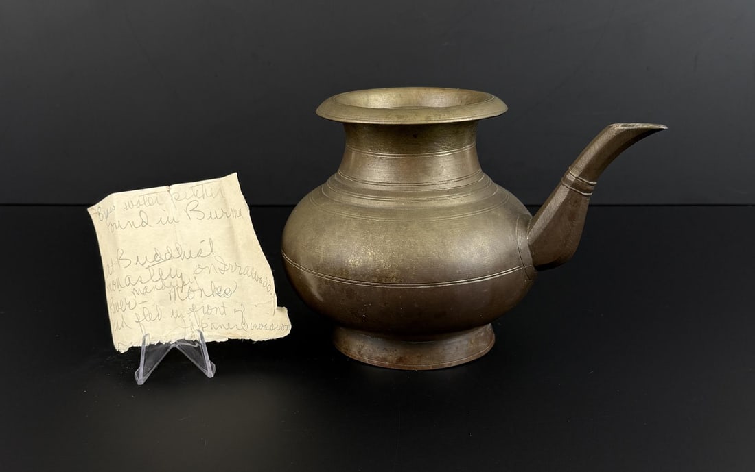 South Asian Kini Brass Water Pot: 7 1/8" by 5 3/4" by 5 3/8". Sold with a note stating the pitcher was found in Burma at a Buddhist Monastery near the Irrawaddy River in Mandalay. The note refers to Monks fleeing from a Japanese
