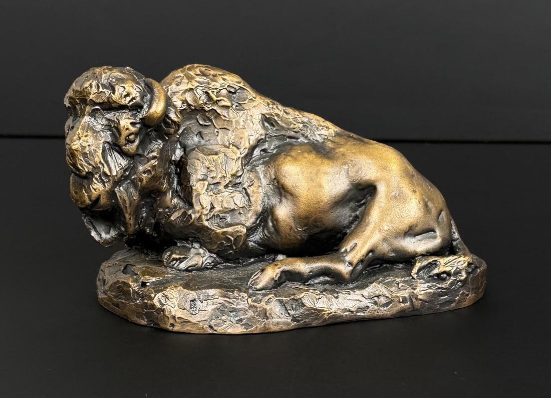 Daro Flood Reclining Buffalo Bronze: Title is Reclining Buffalo. 4 1/2" by 2 1/2" by 2 1/2". 3/30 Daro Flood (1954 - 2017) was active/lived in Arizona. Daro Flood is known for Portrait bust Indian and cowboy sculpture. Daro Flood was a