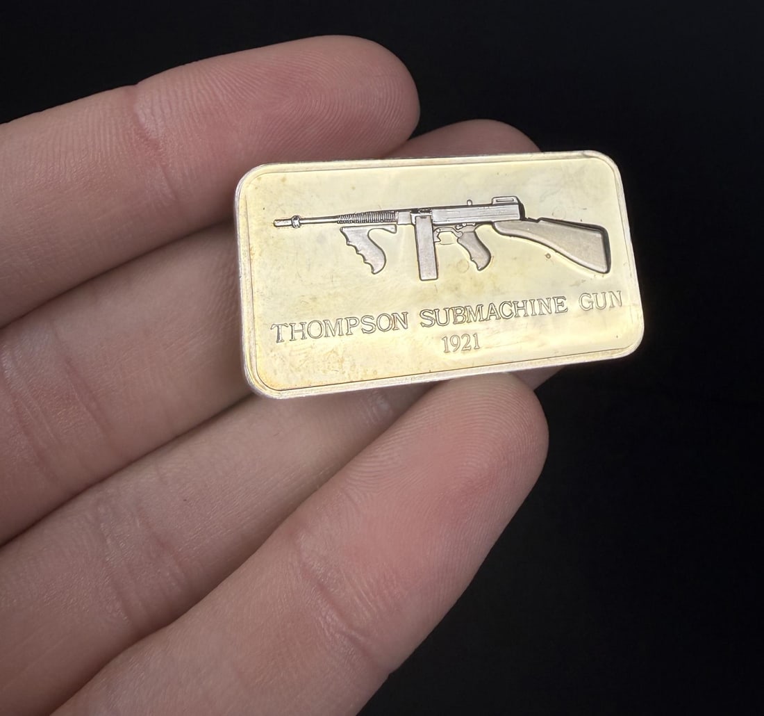 Lincoln Mint Thompson SMG 1oz Silver Bar: Issue No. 2 of the American Weapons Hall of Fame by the Lincoln Mint. The Thompson Submachine Gun, Model of 1921. 32.43 grams of 24K Gold Plated Silver. Measures 1 5/8" by 7/8"