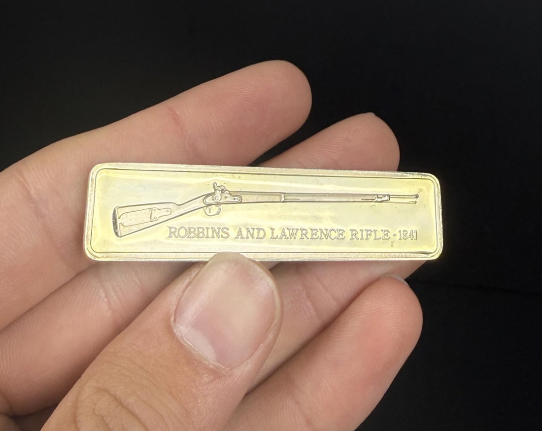 Lincoln Mint R&L 1841 Rifle 1oz Silver Bar: Issue No. 5 of the American Weapons Hall of Fame by the Lincoln Mint. The Robbins & Lawrence Percussion Rifle, Model of 1841. 30.93 grams of 24K Gold Plated Silver. Measures 2 3/8" by 5/8"