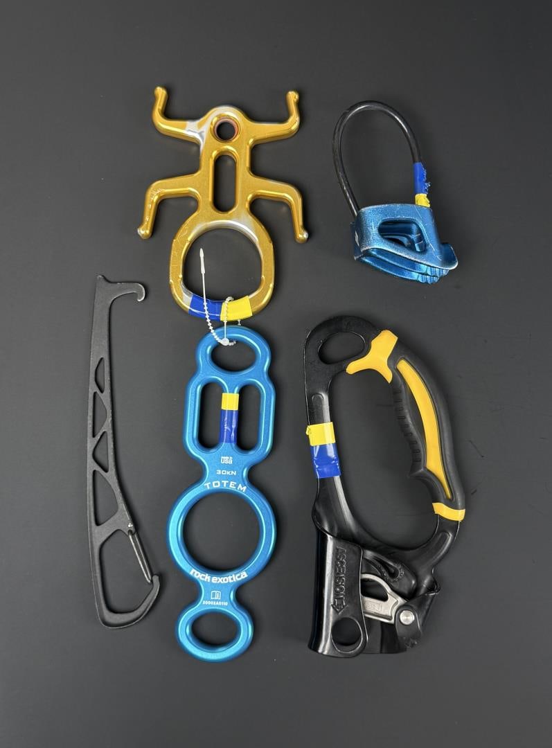 Collection of Mountain Rock Climbing Tools: Petzl Ascension handled ascender, Rock Exotica Totem, lack Diamond Wiregate Nut Tool, Imlay Canyon Gear Critr3 Rappel Device, Black Diamond ATC-XP belay device.