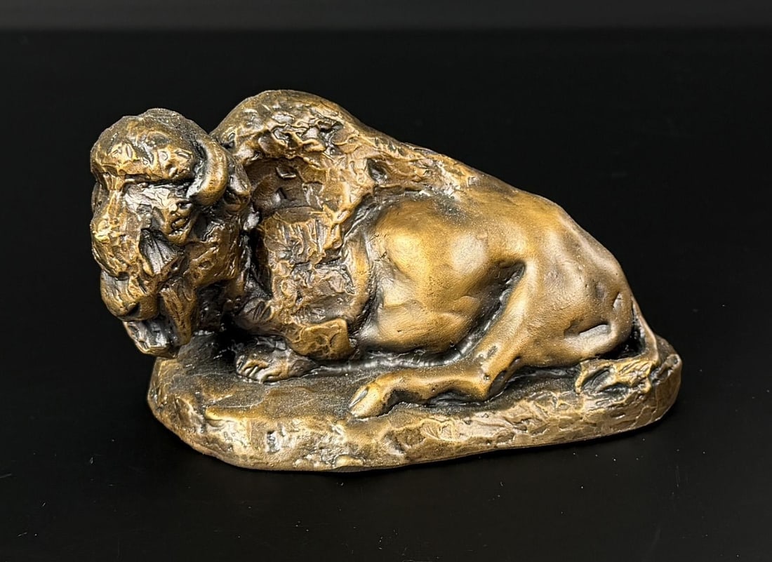 Daro Flood Reclining Buffalo Bronze: Title is Reclining Buffalo. 4 1/2" by 2 1/2" by 2 1/2". 14/30 Daro Flood (1954 - 2017) was active/lived in Arizona. Daro Flood is known for Portrait bust Indian and cowboy sculpture. Daro Flood was a