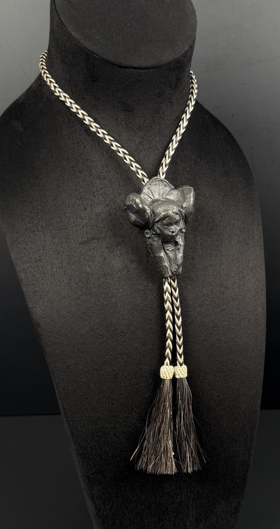 George Carlson 1997 Prix de West Bronze Bolo Tie: Title is Hopi Maiden. 19 1/4" long on ribbon. George A. Carlson (Born 1940) is active/lives in Idaho, Illinois, Colorado. George Carlson is known for Landscape painting, sculpture and drawing. George 