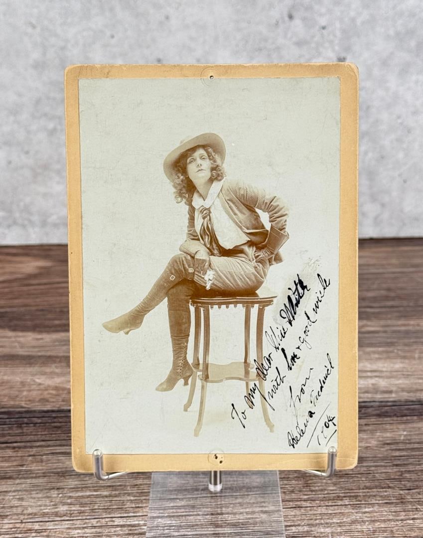 Helena Frederick Signed Actress Cabinet Card: This cabinet card of Helena Frederick shows the actress in a relaxed pose as a pistol packing mama. She poses from the Broadway musical The Tenderfoot. Here she wears knee-high boots, gauntlet gloves,