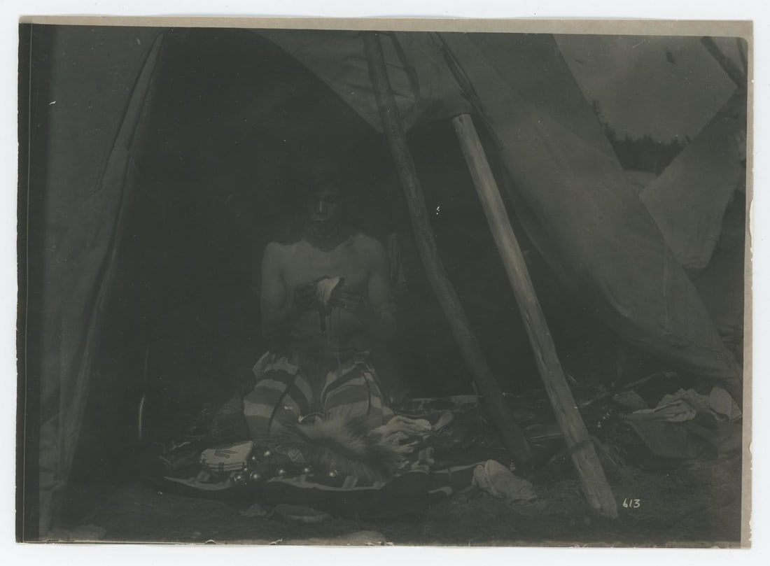 Edward Boos Flathead Indian Montana Photo: 5" by 7". Eneas Conko (Go-Go) preparing for the dance. Boos #613. Man pictured in entrance to tipi assembling clothing. Boos' Flathead Reservation portraits document particularly insightful details re