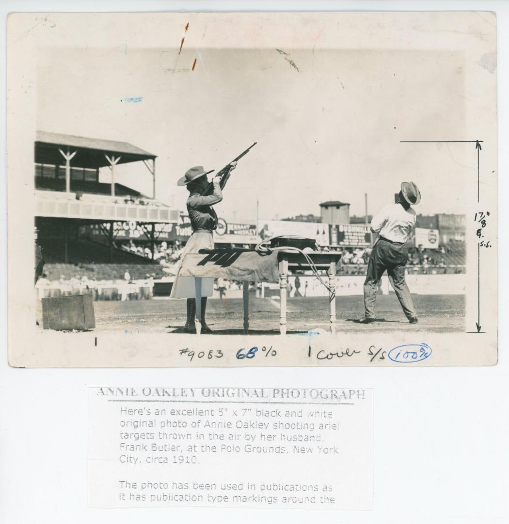 1910 Annie Oakley Polo Grounds Shooting Photo: 5" by 7". Nice original press photo. Annie Oakley competing in a trapshooting exhibition at the Polo Grounds in New York City in 1910. She is shown aiming a Remington Model 12 .22 caliber pump-action 