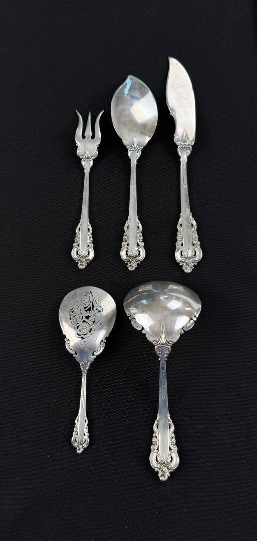Wallace Sterling Silver Grande Baroque Flatware: Includes gravy ladle, nut spoon, pickle fork, jelly spoon, and butter knife all in the Grande Baroque Sterling design introduced by Wallace Silversmiths in 1941. 230 grams. Lot requires payment via