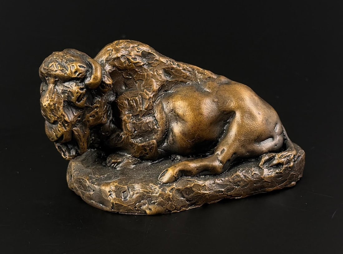 Daro Flood Reclining Buffalo Bronze: Title is Reclining Buffalo. 2 1/2" by 2 1/2" by 4 1/2". Number 10/30. Daro Flood (1954 - 2017) was active/lived in Arizona. Daro Flood is known for Portrait bust Indian and cowboy sculpture. Daro Floo