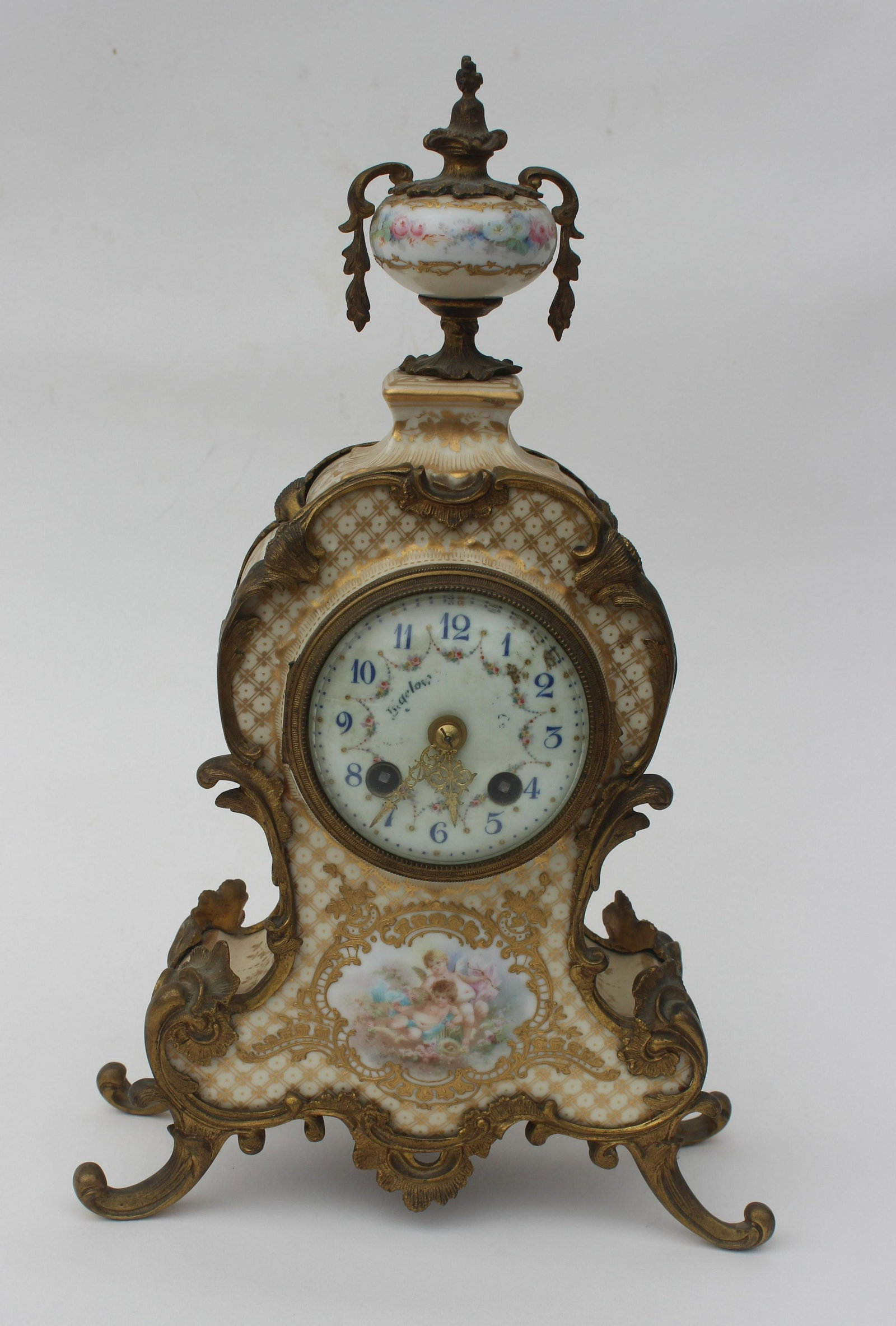 FRENCH PORCELAIN & ORMOLU MANTLE CLOCK: French mantle clock has a hand painted scene with cherubs & flowers with gilded highlights, wonderful ormolu mounts w/urn top. The works are marked Medaille d'Argent 1855. Condition the face shows wea