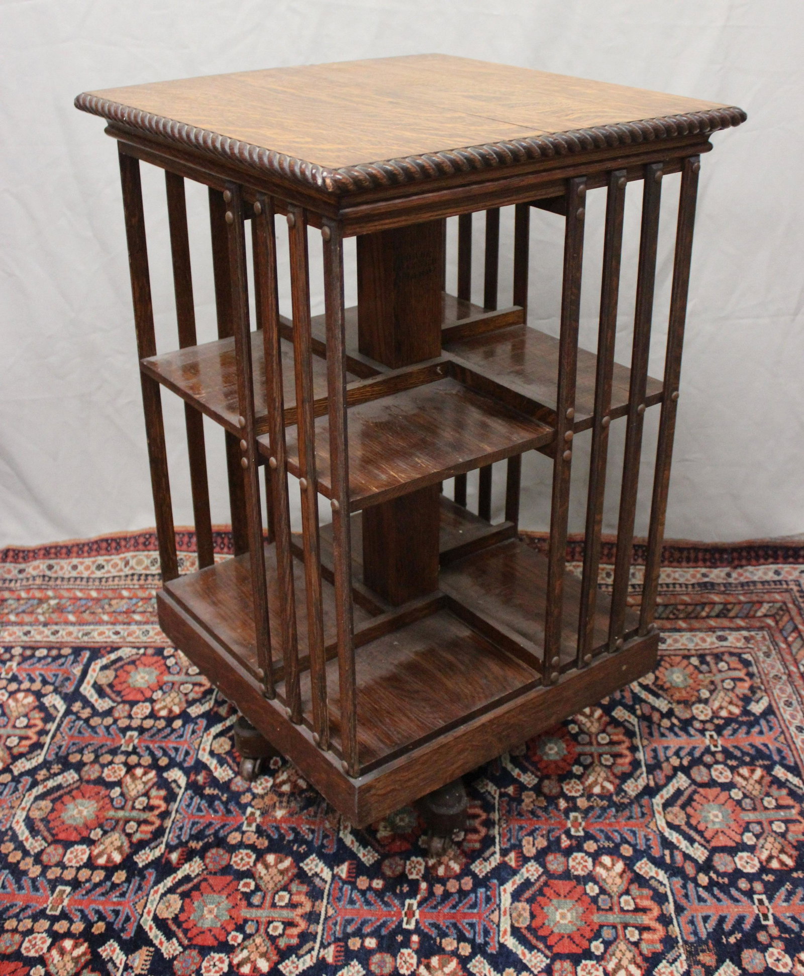 VICTORIAN OAK REVOLVING BOOKCASE: Wonderful golden oak revolving bookcase on a pedestal base with castors, rope molded top with brass tack decoration on side slats. size 35" H x 28'5" wide, Top shelf 10" H x 7"D x 10" W, bottom shelf
