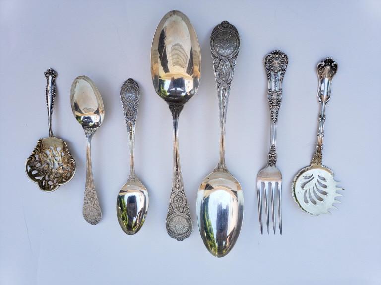 GROUPING OF STERLING SILVER UTENSILS: Seven pieces total, 2 tablespoons & 2 teaspoons same pattern, Shell pattern fork, lemon server & a bonbon spoon. 8.4 troy ounces. Good condition, consistent with age