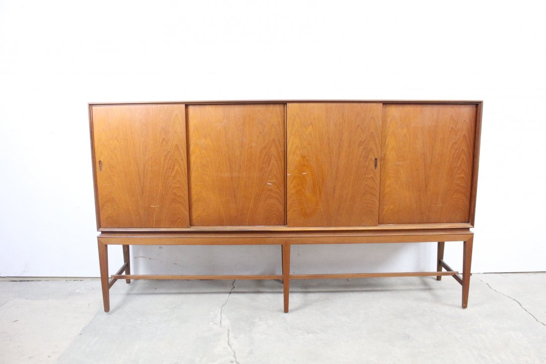 Mid-century Modern Teak Wood Credenza, Sliding Front: Mid-century modern teak wood credenza with sliding front doors and two wide drawers above. Vertical wood grain and warm wood tones give this attractive piece a presence in any room. Dimensions are 44.
