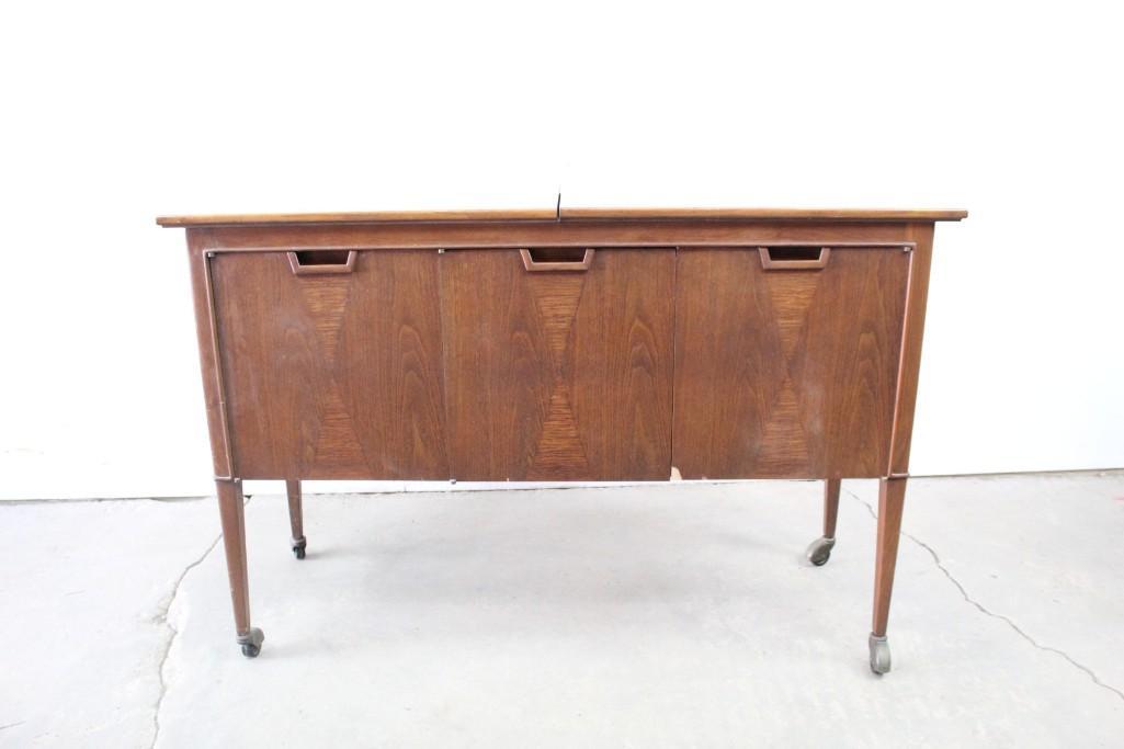 Mid-century 3-Door Wood Expanding Wheeled Credenza: Mid-century modern wood credenza or cabinet with three doors and various internal compartments, as well as a top surface that slides left and right to reveal an additional middle surface when needed. 