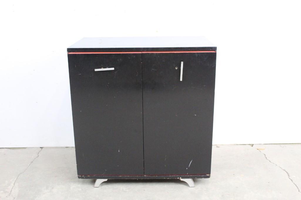 Minimalist Black Lacquer Art Deco 2-Door Cabinet: Minimal black painted cabinet with silver details. This simple, sleek cabinet has a pop of color from the red interior. It would fit in well in any room in the house. The dimensions are 32.5in h x 30i