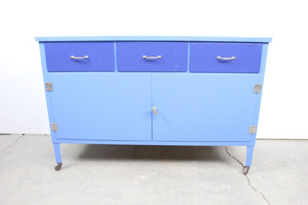 Mid-Century Modern Blue Painted Metal Rolling Cabinet: Minimal blue painted metal credenza with wheels. This simple blue credenza has clean lines and simple shapes that will look great in any room. It has wheels for extra convenience. The dimensions are 3