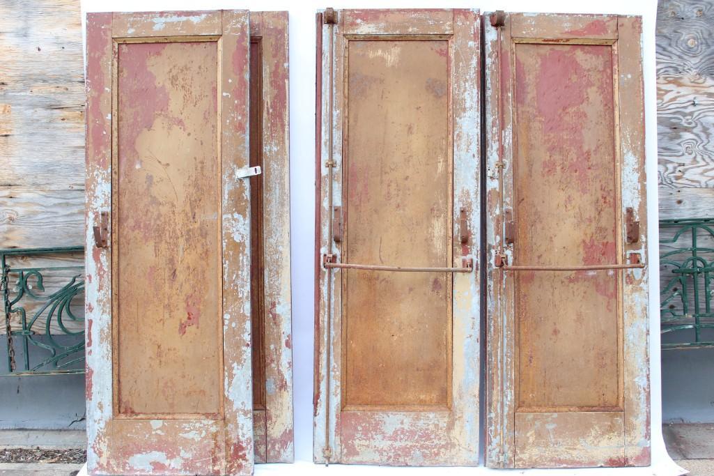 Two Pairs of Red Painted Metal Double Theater Doors: Two pairs of metal double doors with an eye-catching patina of worn paint in contrasting shades of red and grey. These came from an old theater building in Kingston NY. Ready to incorporate creatively