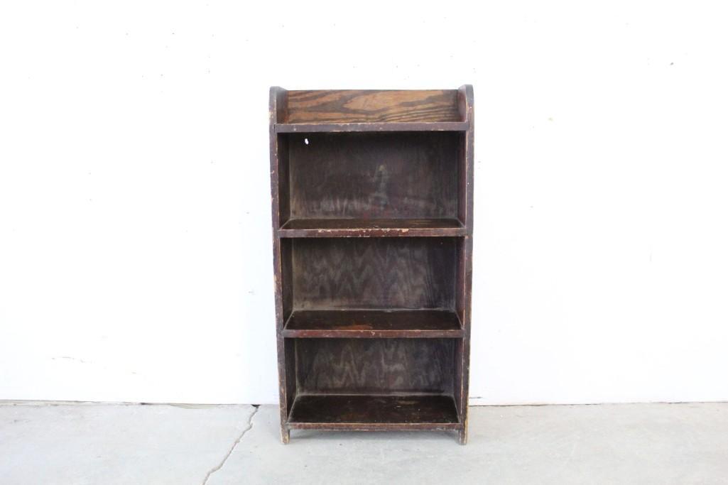 Small Four Tiered Dark Brown Wooden Shelf: Small four tiered dark brown wooden shelf. This shelf would bring a classic feel to any living space. Dimensions are 36 in h x 19.25 in w x 7 in d. Condition is good, with minor surface wear. Please c