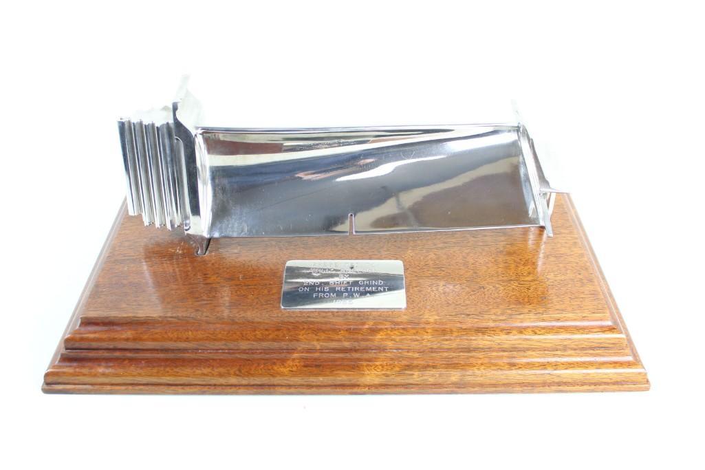 Titanium-Plated Presentation Engine Model Plaque: Titanium-plated presentation model of what appears to be part of an engine turbine, as part of a plaque given in 1985 to a man who worked what the label refers to as the "second shift grind."
