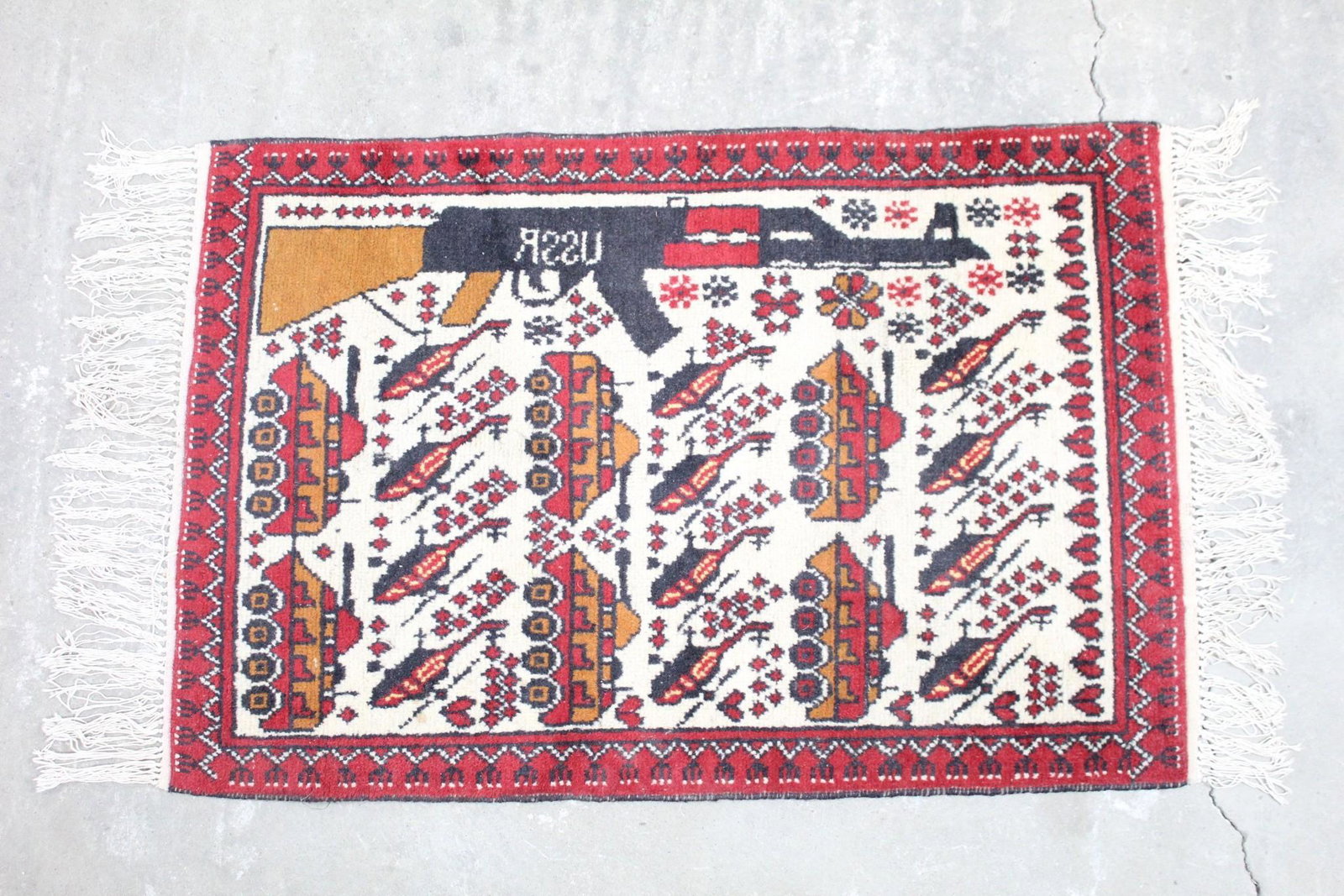 Red Wool Afghan Soviet War Rug w/Gun,Tanks & USSR: Afghan Patterned Gun Tank Military USSR Soviet Rug. This is an Afghan rug with a highly unique design. There are images of flowers, tanks, helicopters, and a large AK rifle with "USSR" imprinted backw