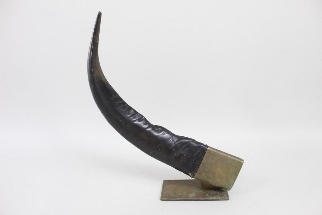 Brass-Mounted Faux Water Buffalo Horn Bookend Sculpture: Brass-Mounted Faux Water Buffalo Horn Bookend Sculpture. A large faux horn, possibly made of cast resin, mounted on a brass base. Could be used a single bookend or enjoy simply as a decorative object.