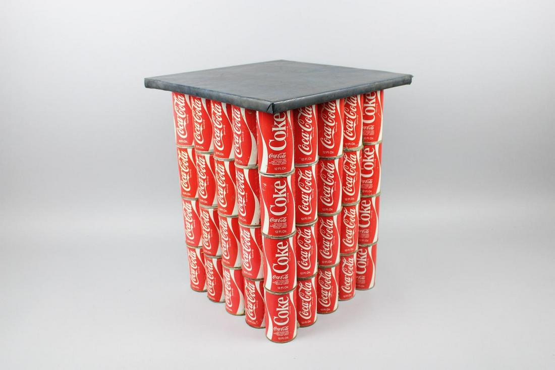 Mid-Century Coca Cola Coke Can Found Art Side Table: Mid-Century Coca Cola Coke Can Found Art Side Table. Unique piece features a base made made out of several dozen vintage - circa 1970s - 12 oz. cans of Coca Cola, with the iconic swirl design. Top sur