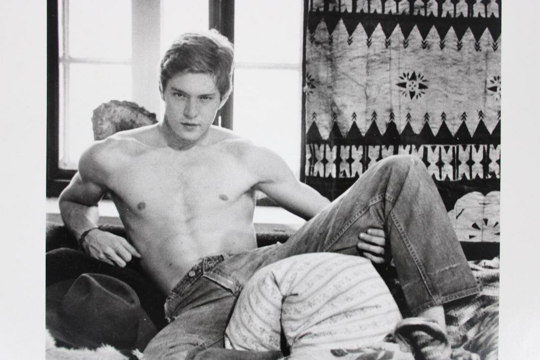 Kenn Duncan Photographs; Shirtless RJ Murray on a Bed 1975: Kenn Duncan American Photographer 1928-1986. Lot of 2 B&W photos of shirtless man in jeans, identified as RJ Murray, on a messy bed. Dated 1975. From the archive of After Dark Magazine. Quantity: 2 Si