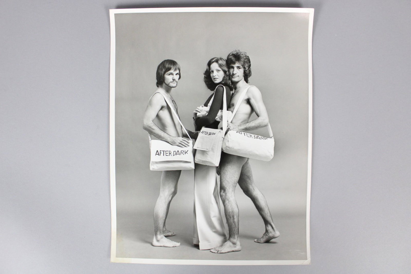 Kenn Duncan Photographs; Models w/After Dark Bags: Kenn Duncan American Photographer 1928 -1986. Lot of 4 B&W photographs of models, some nude, carrying After Dark bags. Undated but from 1968-1983, from the archive of After Dark magazine. Quantity: 4 