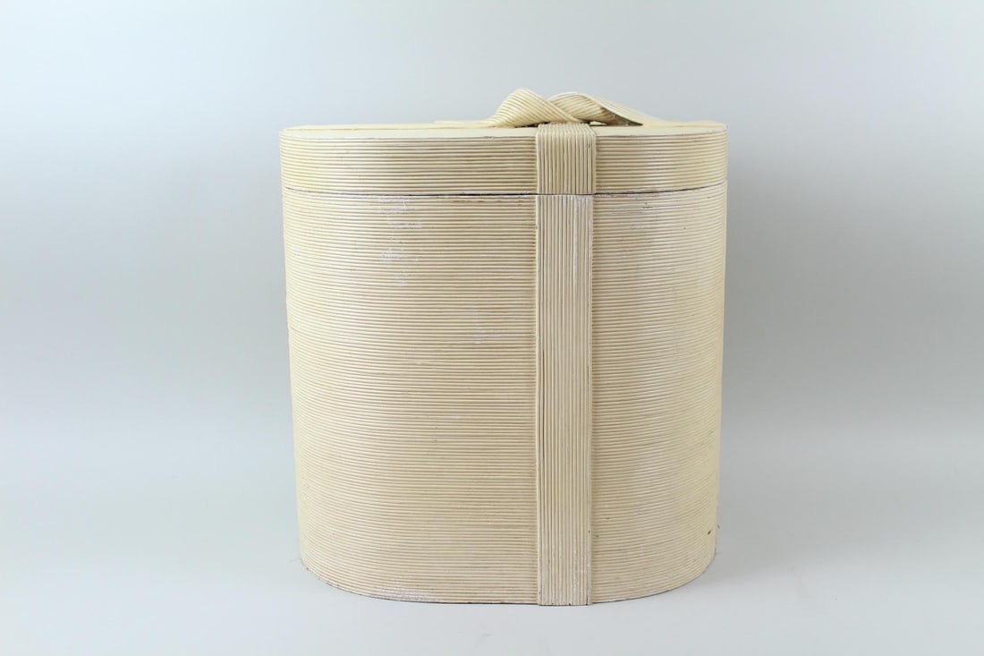 Mid Century Coastal Pencil Reed Oval Ribbon Tied Box: Mid Century Coastal Pencil Reed Oval Ribbon Tied Box. This box has a Hollywood Regency vibe to it, with a lid that comes off. There is a ribbon decoration.Dimensions are 20 in h x 18.25 in w x 12.5 in