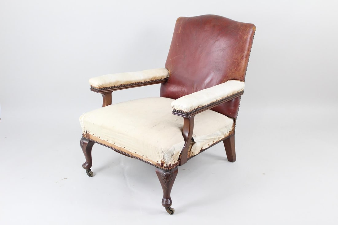 Brown Leather Studded Arm Chair, Deconstructed: Brown Leather Studded Arm Chair. This is a handsome antique armchair. It has brown leather upholstery on its back but deconstructed armrests and seat. It has saber front legs with shells on the curve