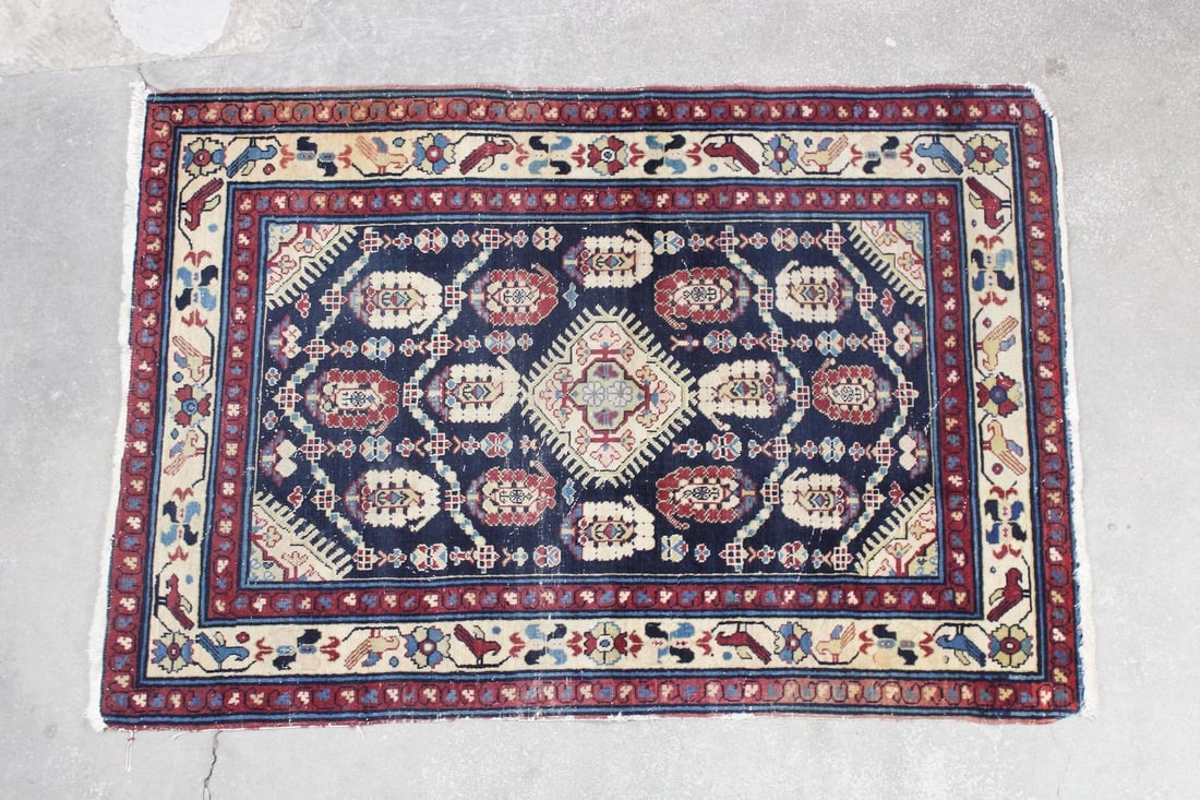 Navy Blue Persian Rug with Birds: Navy Blue Persian Rug with Birds. This hand knotted rug has a busy central field with one large medallion matching the corner accents, surrounded by red and cream colored borders including bird shapes