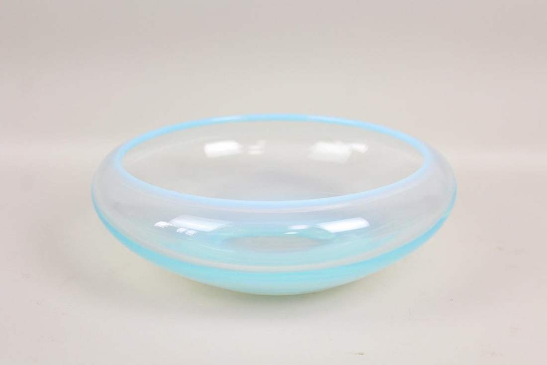 Milk Blue Gradient Art Glass Bowl: Milk Blue Gradient Glass Bowl. This minimalist dish has a glow-like blue tint at the bottom and rim, with a wide opening curled inwards and body tapered to the flattened bottom. Dimensions are 3.5 in 