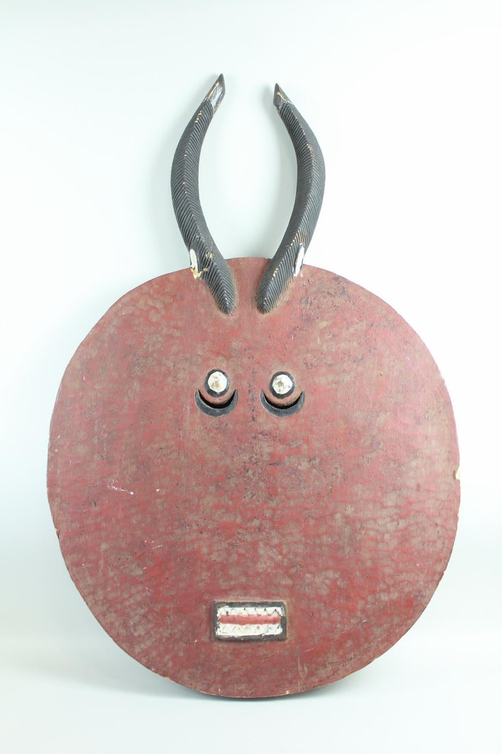 Oversized Painted African Baule Goli Mask, Wooden Horns: Oversized Painted African Baule Goli Mask, Wooden Horns. This 4-foot tall wooden mask is made of a round face painted red with sculptural eyes, teeth, and two horns made of carved wood, with a hollowe
