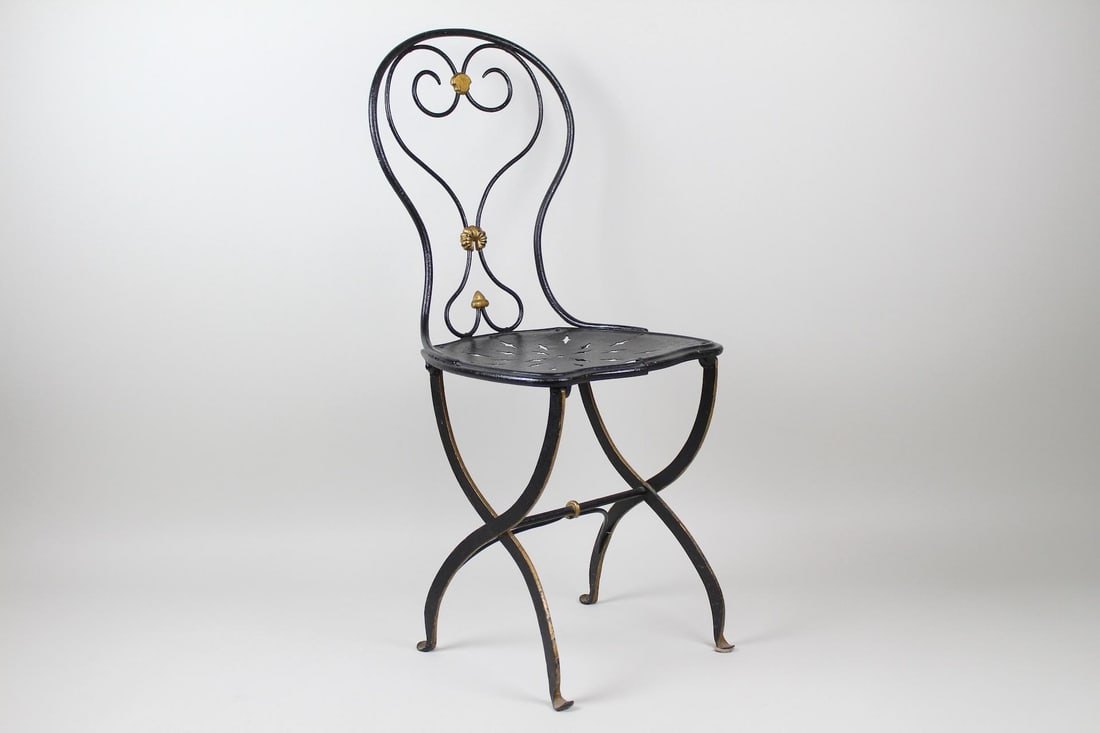 Art Nouveau Iron Bistro Chair: Black Wrought Iron Bistro Chair. This is a handsome black bistro chair. It has a perforated seat and a wrought iron frame. There are gold painted details on the wire back. It is a contemporary paint j