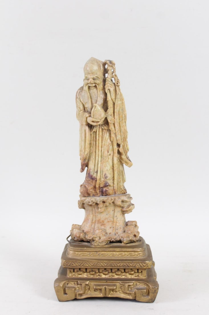 Chinese Carved Soapstone Shou-lao God of Longevity Statue: Chinese Carved Soapstone Shou-lao God of Longevity Statue. Carved stone figure of Shou-lao, the God of Longevity, holding his staff and a peach of longevity. On a brass base. Dimensions are 12.5 in h