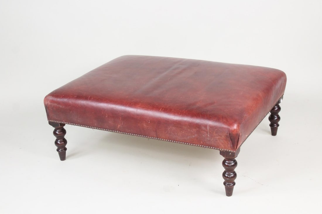 Burgandy Red Leather & Turned Wood Leg Ottoman: Red Leather & Turned Wood Leg Ottoman. This foot rest or broad seat has red leather upholstery that's been studded in place with 4 wooden legs of turned wood with rounded sphere shapes. Dimensions are
