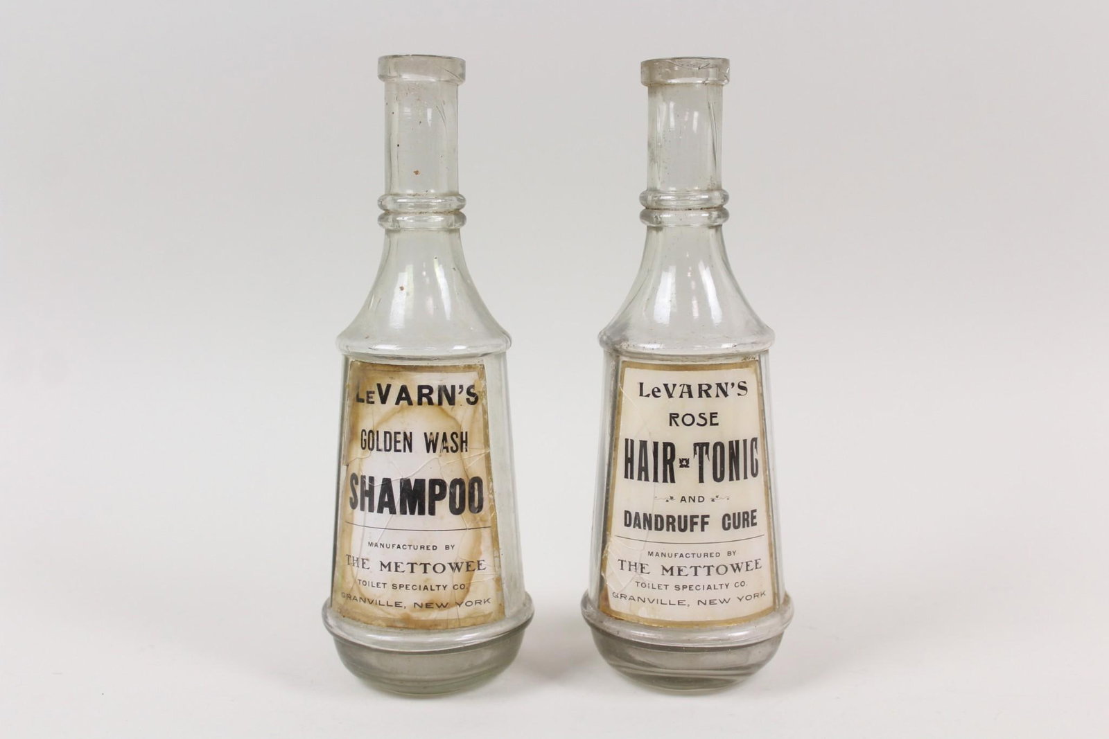 Pair of LeVarn's Barber Apothecary Bottles: Pair of LeVarn's Barber Apothecary Bottles, Label Under Glass. Includes a clear glass bottle forLeVarn'sGolden Wash Shampoo and another for LeVarn'sRose Hair Tonic byMettowee Toilet Specialties of Gra