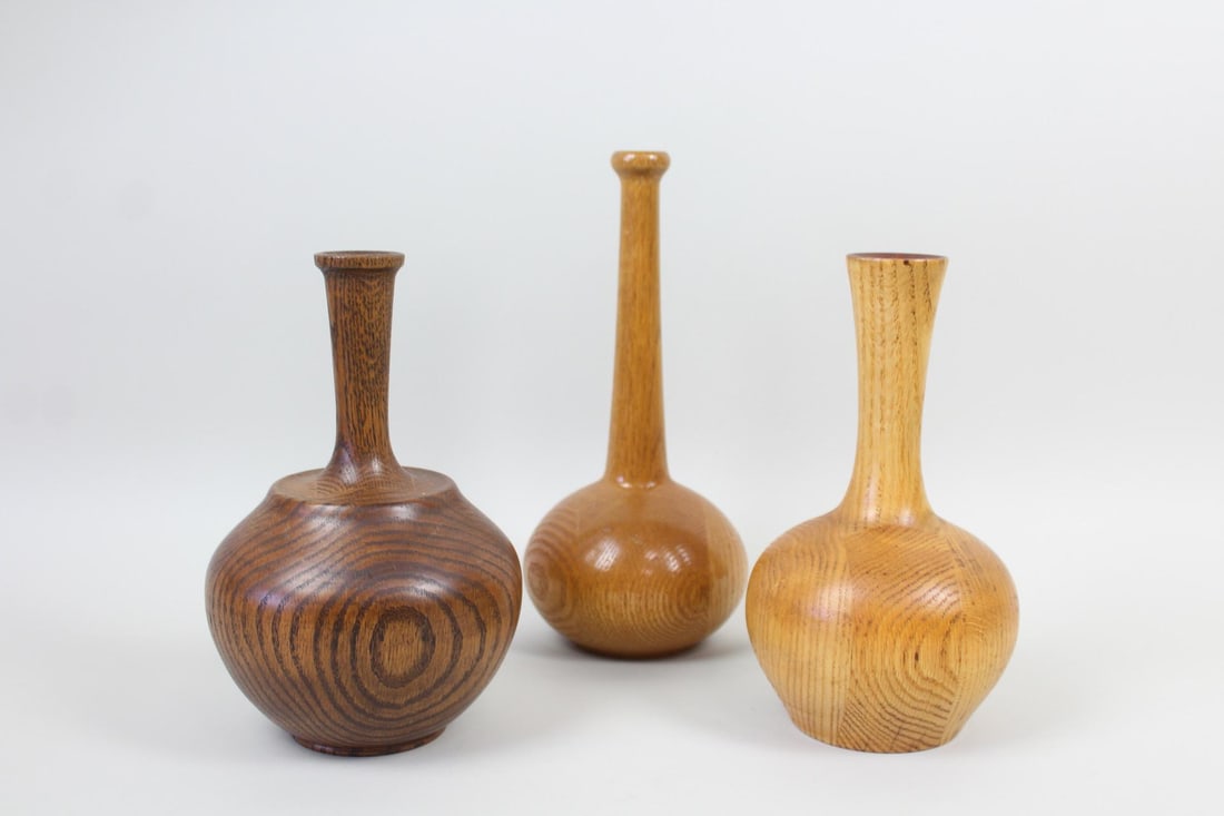 Lot of 3 Turned Wood Bud Vases: Lot of 3 Turned Wood Bud Vases. These small wooden vessels have differing onion shaped bodies with long necks and narrow openings with varying designs. One is marked underneath as Stan B. 2. 2.1996. D