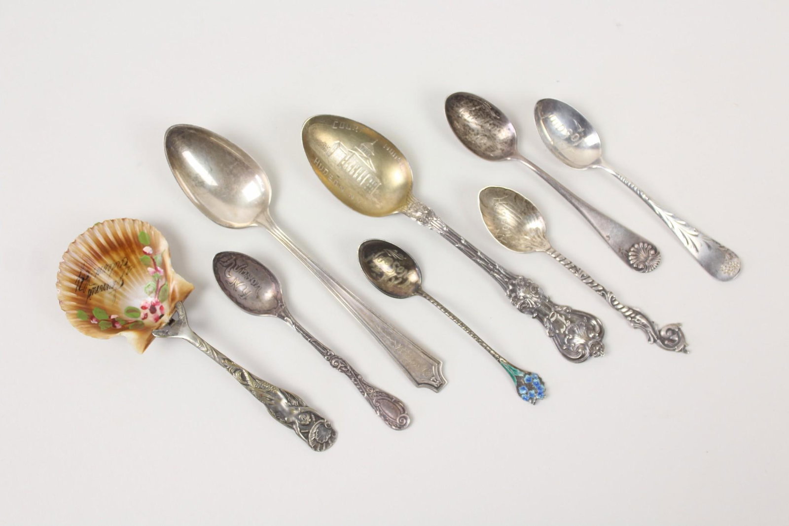 Collection of 8 Hudson NY Silver Souvenir Spoons: Collection of 8 Hudson NY Silver Souvenir Spoons. Eight turn of the 20th century souvenir spoons from Hudson NY. Most marked sterling. Notable is an Art Nouveau spoon with a mermaid handle and painted