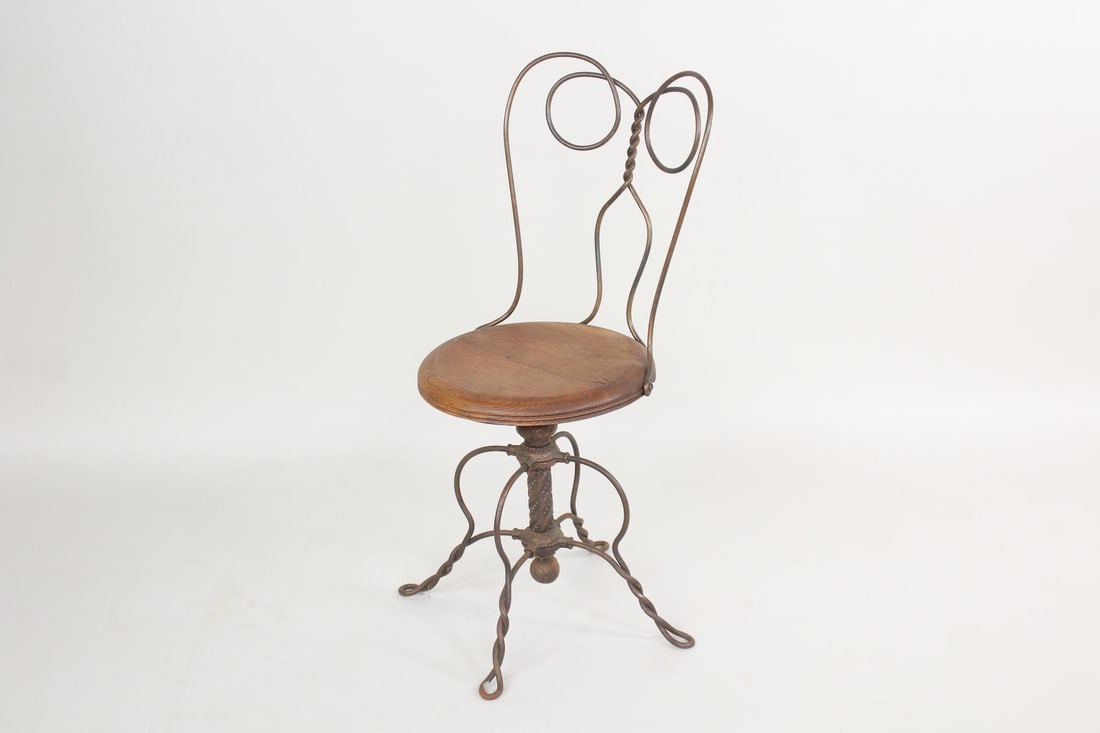 Twisted Iron Ice Cream Parlor Swivel Chair: Victorian Twisted Iron Ice Cream Parlor Swivel Chair. Chair has a framed of twisted iron, with a wooden seat and ornate cast iron swivel mechanism. Dimensions are 35 in h x 14.5 in w x 15.5 in d. Cond