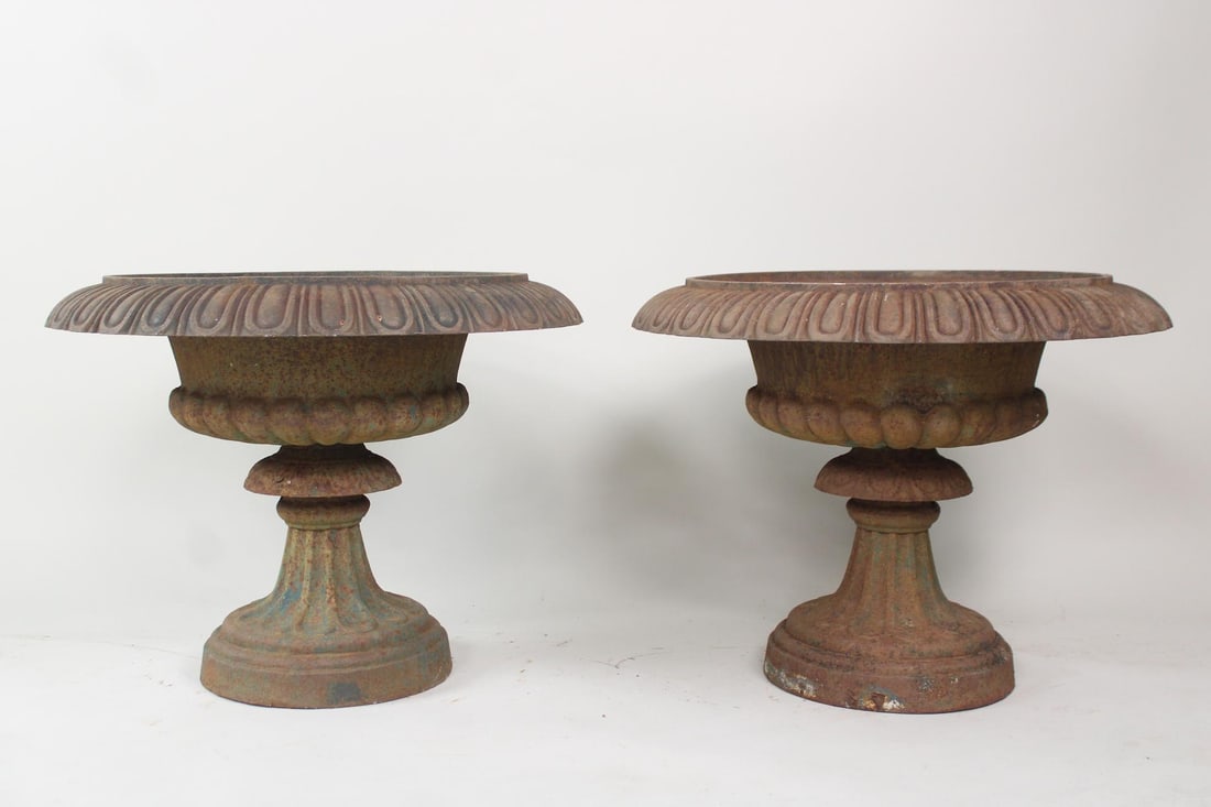 Pair of Wide Cast Iron Urn Planters on Pedestal: Pair of Cast Iron Urn Planters on Pedestal, minor remnants of green paint. Great wide iron planters, nice patina to the surface. Dimensions are 19 in h x 25 in w x 25 in d. Condition is good overall.
