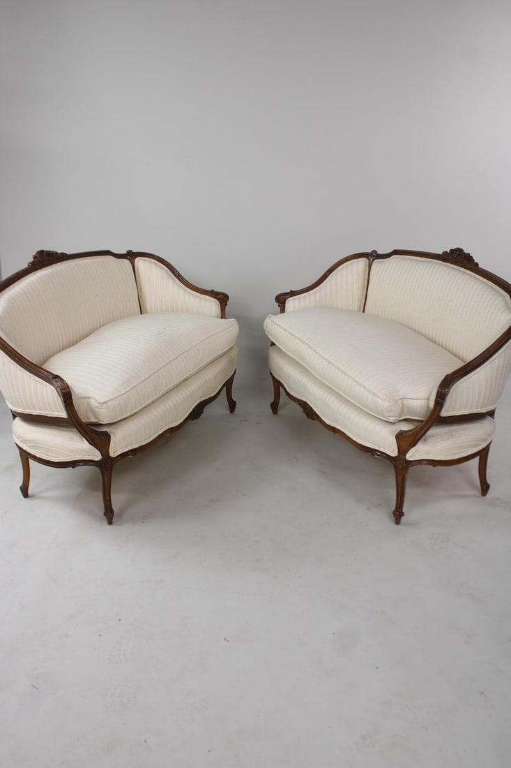 Pair of Louis XV Carved Upholstered Settees: Pair of Louis XV Carved Upholstered Settees. Matching pair of French style settees with ornately carved frames and cream colored striped upholstery. Feather and down cushions are plush and comfortable