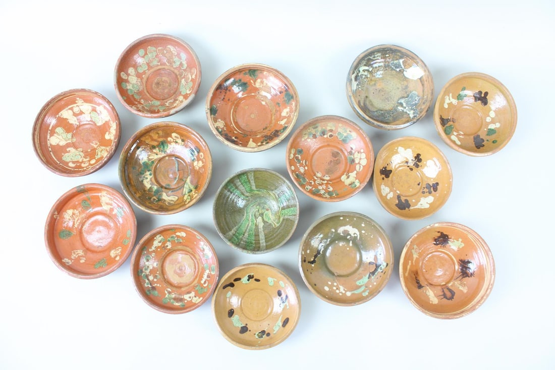 Group of 14 Redware Slip Decorated Bowls: Group of 14 Redware Pottery Slip Decorated Bowls. Fourteen round redware bowls, with slip decoration in green, brown and white. Dimensions are 2.5 in h x 6.25 in w x 6.25 in to 2.5 in h x 7 in w x 7 i