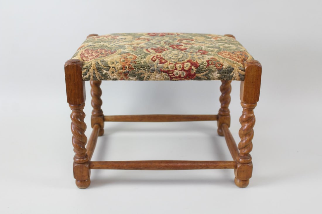 Wooden Barley Twist Footstool with Floral Upholstery: Wooden Barley Twist Footstool or Ottoman with Floral Upholstery. A petite stool with a warm grained wood frame, likely oak, and four barley twist turned wood legs. Covered in a tapestry-style floral p