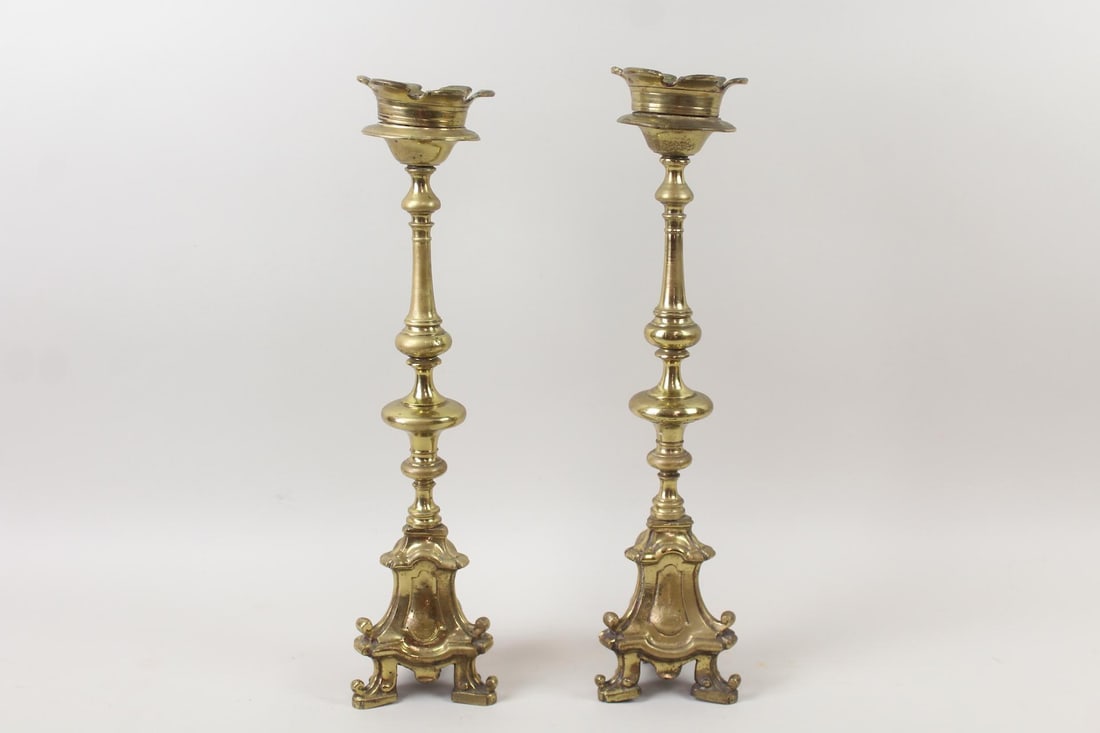 Pair of Ornate Brass Candlesticks with Engraved Animals: Pair of Ornate Brass Candlesticks with Engraved Animals. Matching pair of candlesticks with tripod bases, and engraved animals on the sides. Dimensions are 22.25 in h x 5.5 in w x 5.5 in d. Condition