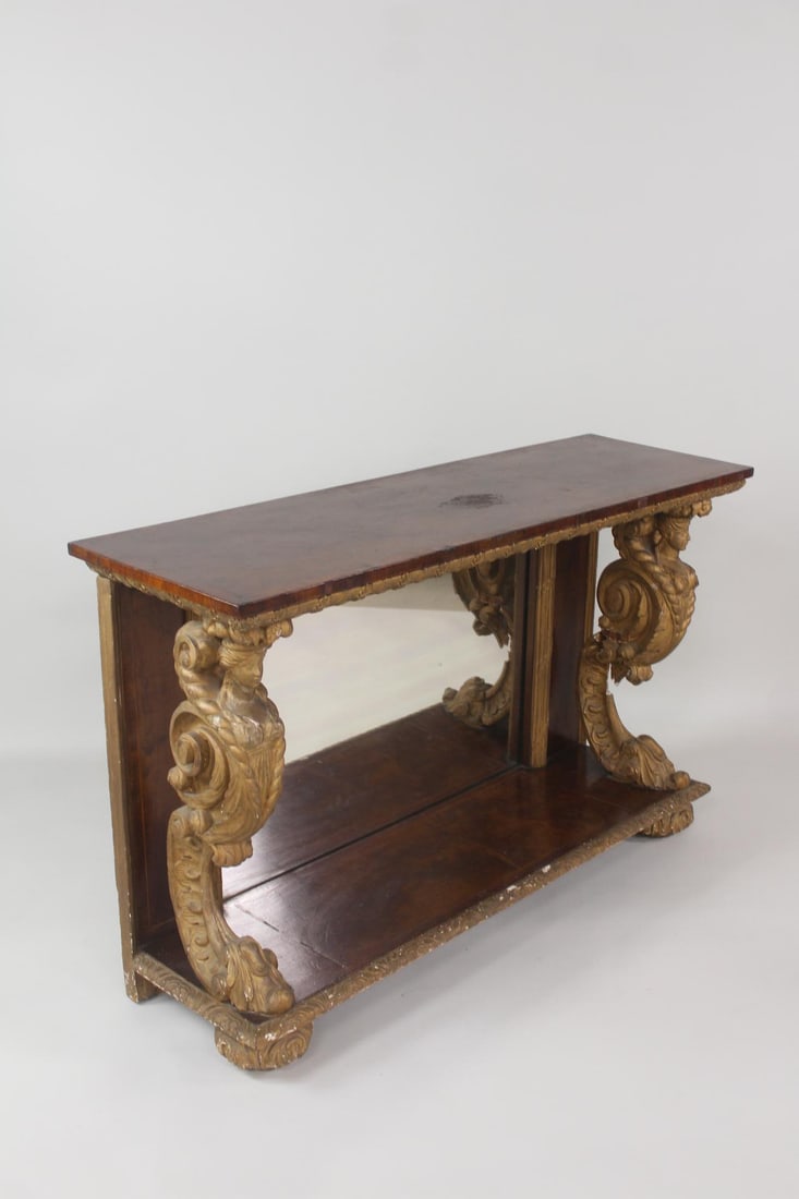 Empire Mirrored & Gilt Carved Wood Figural Woman's Heads Console Table: Empire Mirrored & Giltwood Figural Console Table. Elaborate console table made of wood, with gilt decorative figural supports and a mirrored back. Dimensions are 31.75 in h x 50.5 in w x 15.75 in d. C