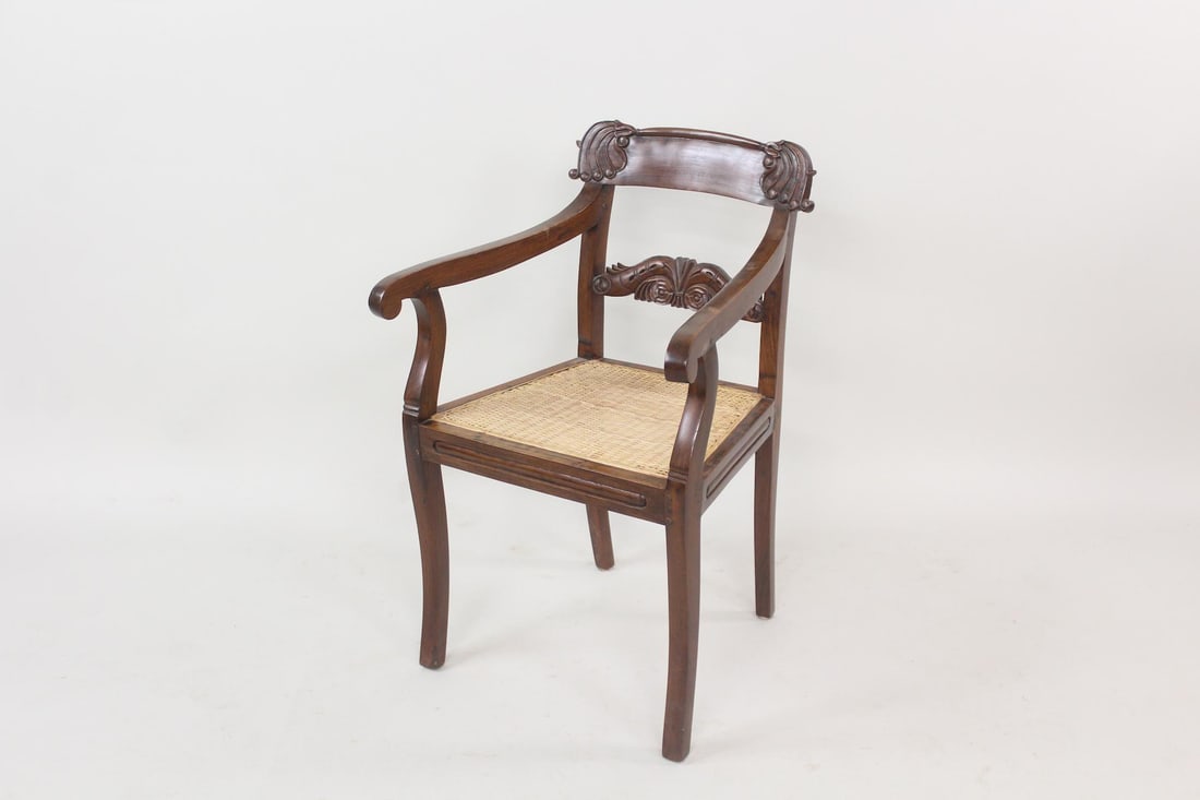 Neoclassical Carved Wood Armchair with Caned Seat: Neoclassical Carved Wood Armchair with Caned Seat. Chair with wooden frame, scrolled carving on the backrest and newer woven rattan or cane seat. Dimensions are 33 in h x 21 in w x 19 in d. Condition 