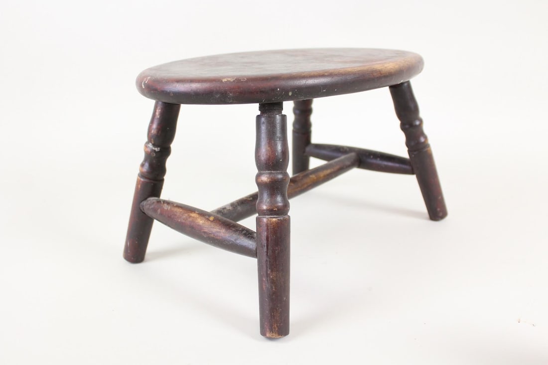 Diminutive Wooden Stool with Turned Legs: Diminutive Wooden Stool with Turned Legs. Sturdy little stool with oval top, 4 turned legs and cross brace. Great patina. Dimensions are 8 in h x 13.25 in w x 9 in d. Condition is good with minor scra