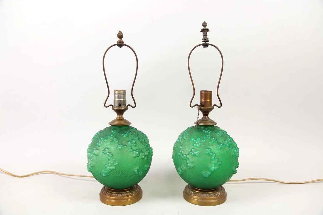 Pair of Green Glass Globe Table Lamps with Grape Clusters: Mid-century Modern Globe Lamps. Two table lamps with emerald colored glass globes and a bumpy grape cluster textured surface. Two different sized harps and finials. Dimensions are 19.25 in h x 7 in w